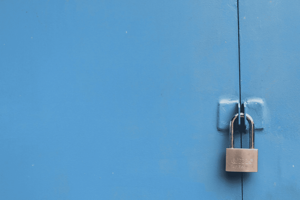 A baby blue coloured door locked with a gold padlock
