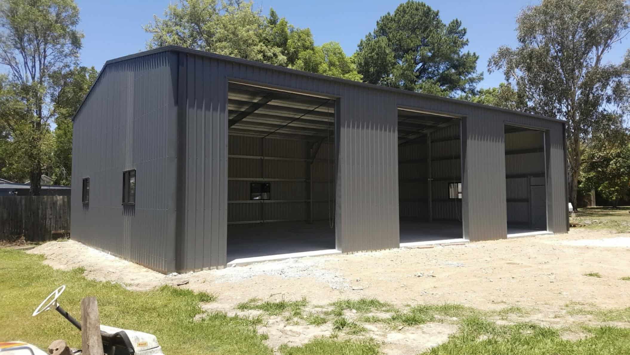A large metal shed with three open roller doors